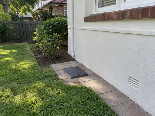 Tiled backyard access cover beside a house wall and lawn in Gladesville